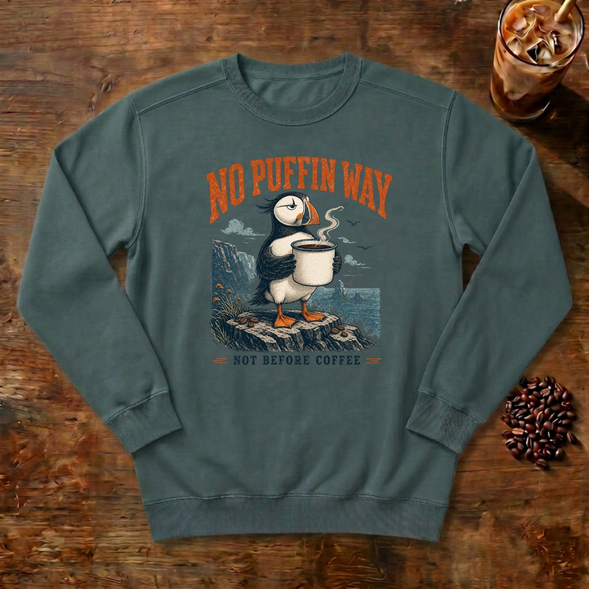 No Puffin Way Sweatshirt in Blue Spruce, a puffin holding a cup of coffee by the coast