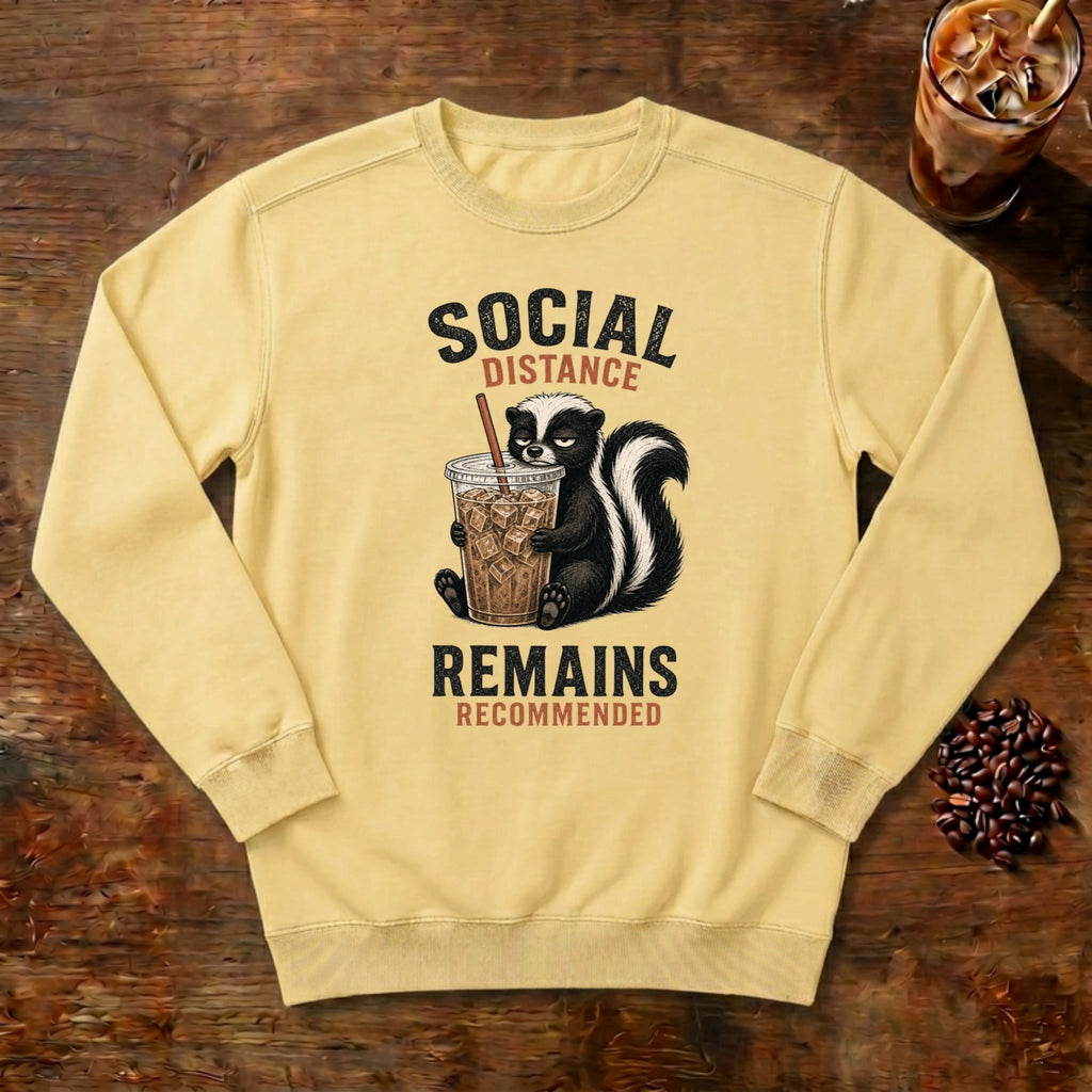 Social Distance Remains Skunk Sweatshirt in Butter, a retro skunk sipping iced coffee