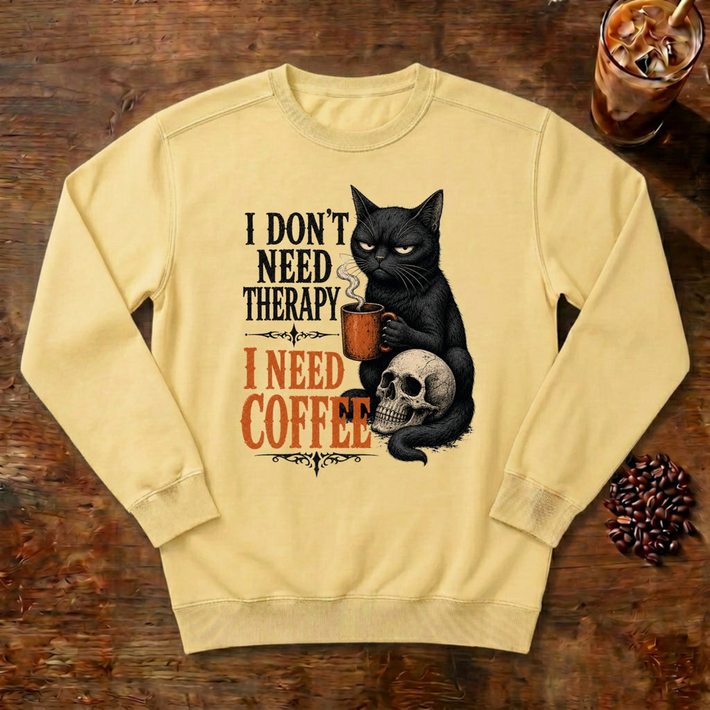 I Don't Need Therapy Cat Sweatshirt in Butter, a black cat holding a coffee mug and sitting on a skull