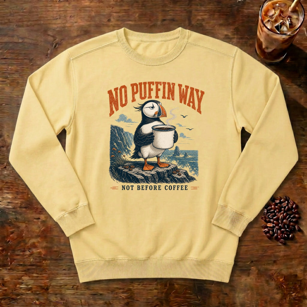 No Puffin Way Sweatshirt in Butter, a puffin holding a cup of coffee by the coast