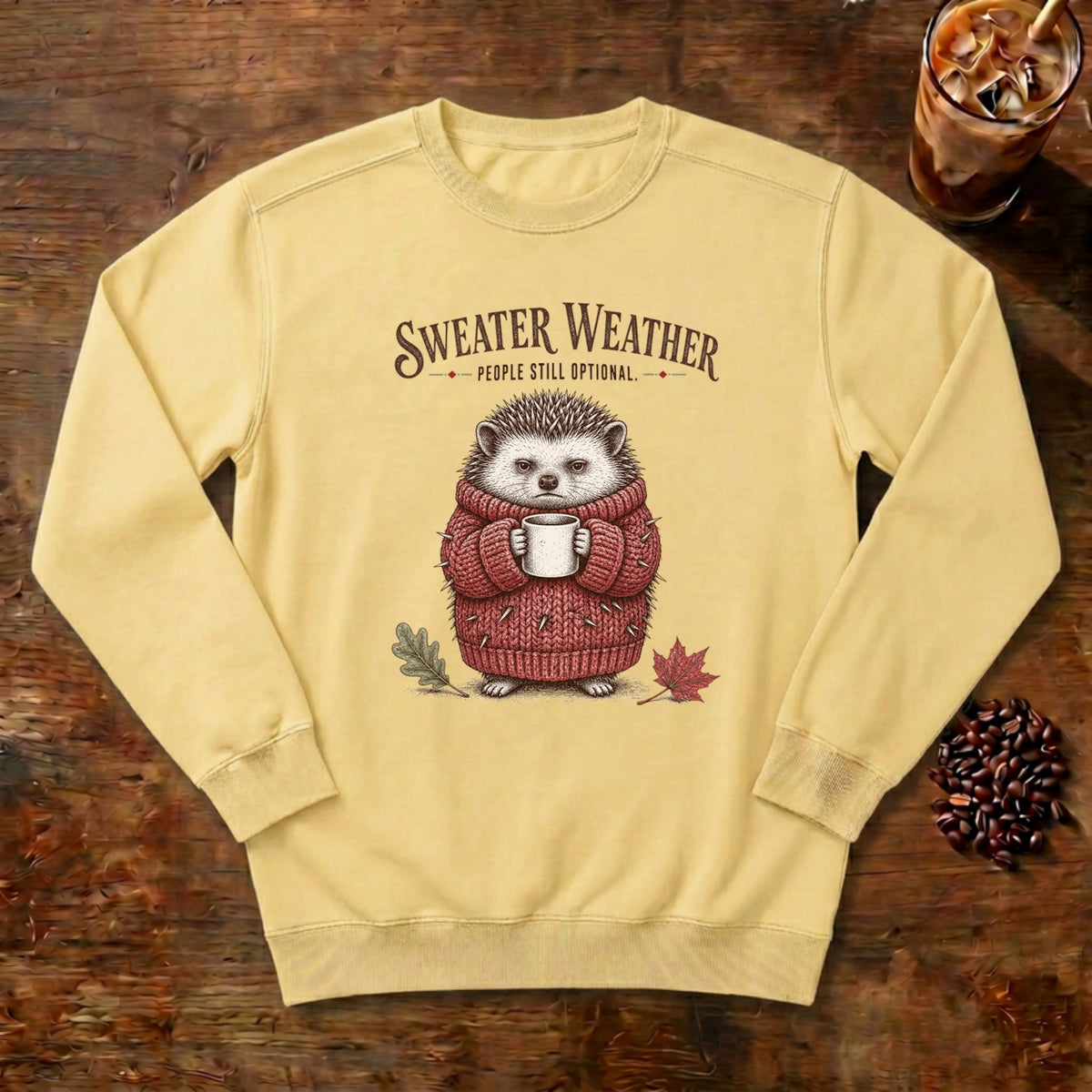 Sweater Weather Hedgehog Sweatshirt in Butter, a hedgehog in a knit sweater holding a mug