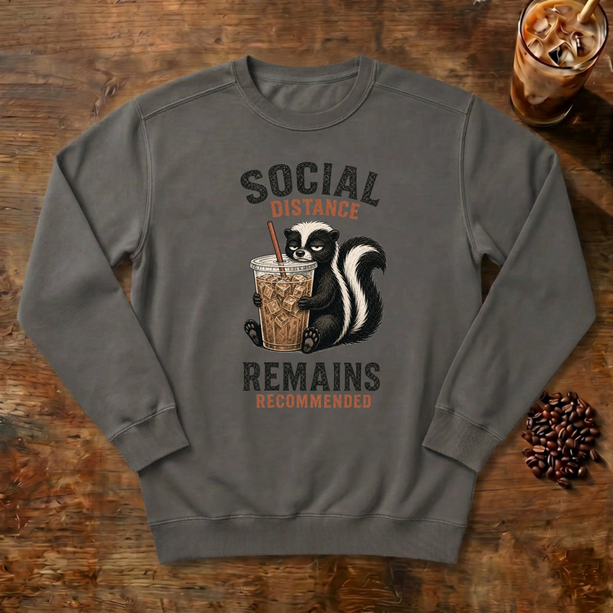 Social Distance Remains Skunk Sweatshirt in Pepper, a retro skunk sipping iced coffee