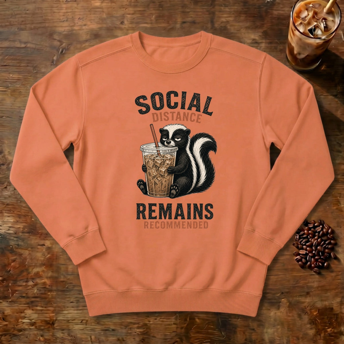 Social Distance Remains Skunk Sweatshirt in Terracotta, a retro skunk sipping iced coffee