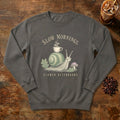 Slow Mornings Snail Sweatshirt in Pepper, a sleepy snail carrying a coffee cup on its shell