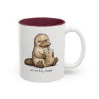 Still Not Fully Charged Platypus Coffee Mug, white with maroon interior. Sleepy platypus sipping iced coffee with “still not fully charged” text