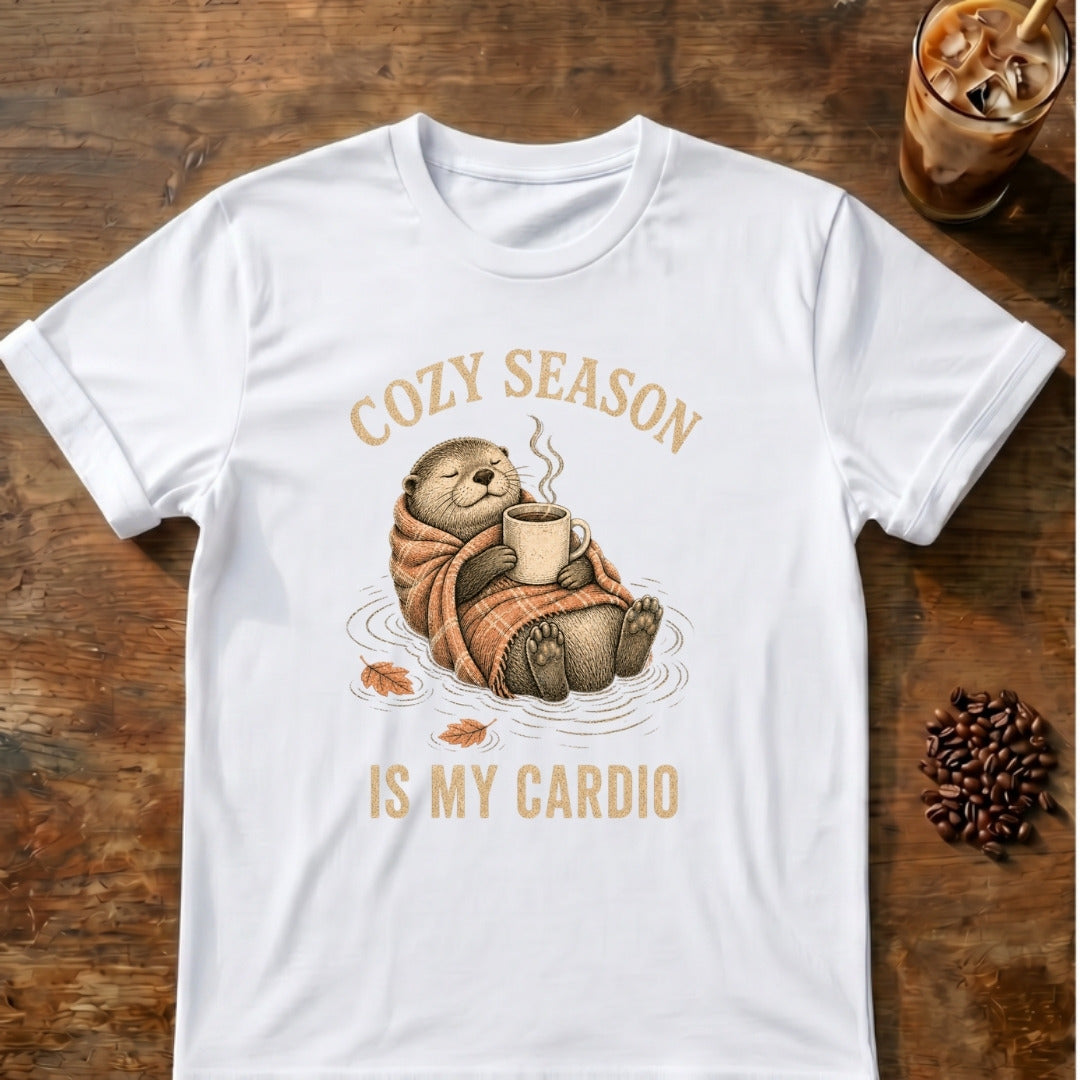 Cozy otter floating on its back wrapped in a plaid blanket holding a steaming mug with the words Cozy Season Is My Cardio on a White T-shirt.