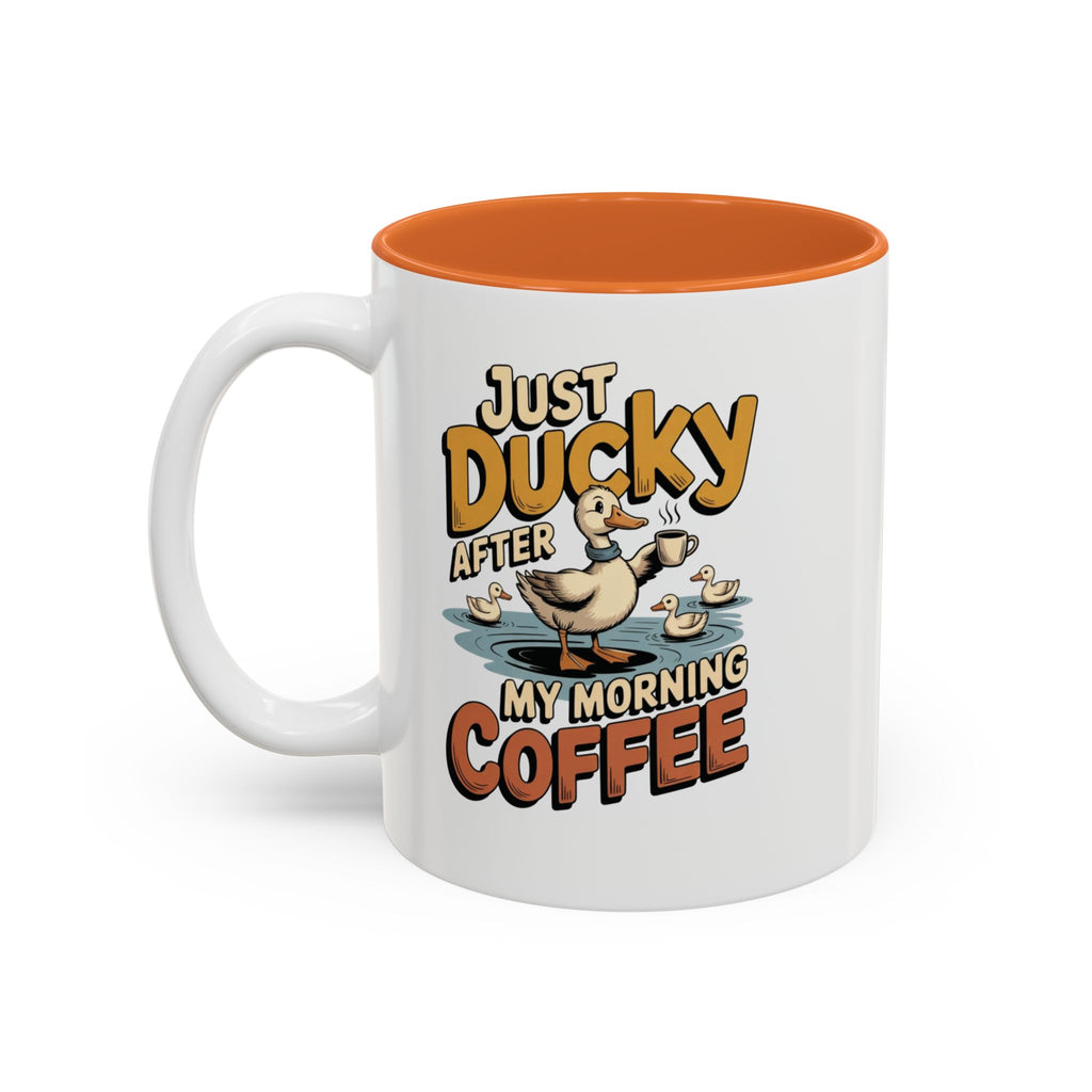 Just Ducky After My Morning Coffee Mug, 11 oz, white with orange interior. Cheerful duck raising a coffee cup in a pond with ducklings and “Just Ducky After My Morning Coffee” text
