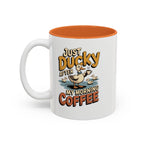 Just Ducky After My Morning Coffee Mug, 11 oz, white with orange interior. Cheerful duck raising a coffee cup in a pond with ducklings and “Just Ducky After My Morning Coffee” text