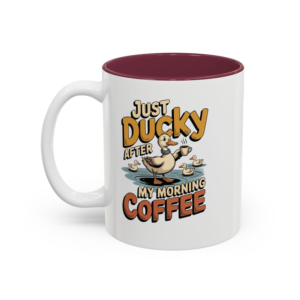 Just Ducky After My Morning Coffee Mug, 11 oz, white with maroon interior. Cheerful duck raising a coffee cup in a pond with ducklings and “Just Ducky After My Morning Coffee” text