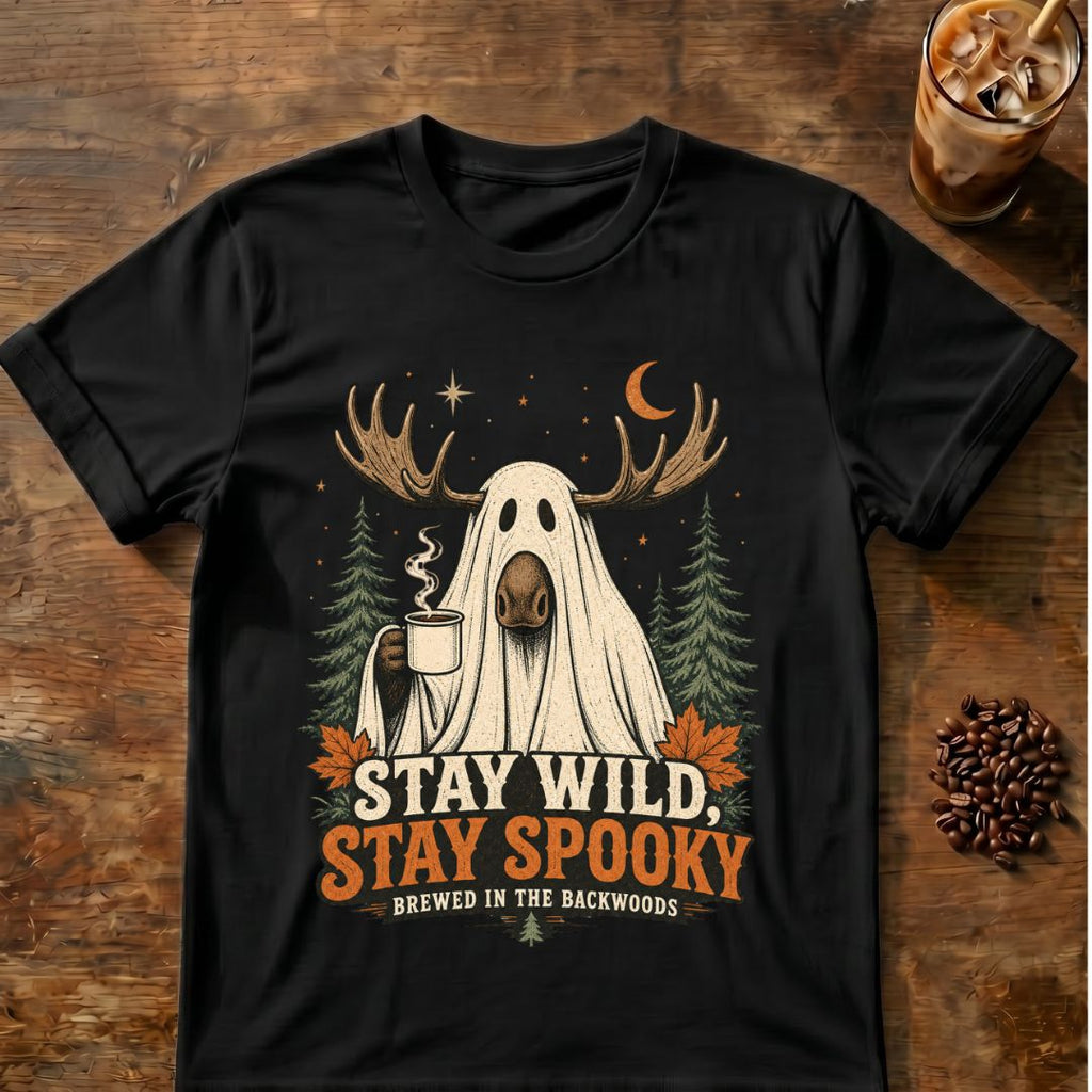 Moose wearing a ghost sheet and holding coffee among pine trees with “Stay Wild, Stay Spooky” text