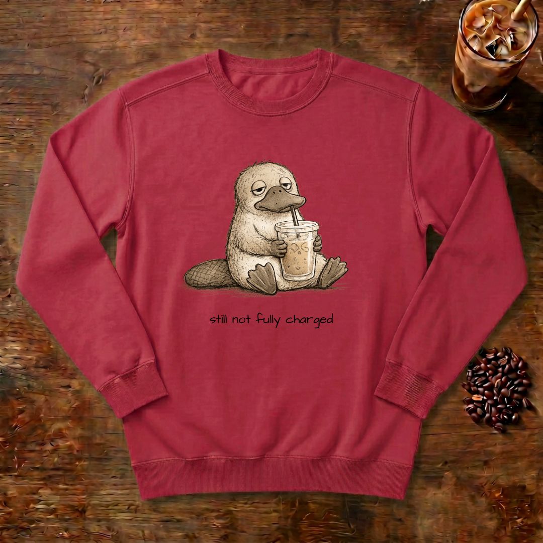 Still Not Fully Charged Platypus Sweatshirt in Crimson, a sleepy platypus sipping iced coffee