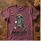 Raccoon coffee graphic on a Heather Maroon T-shirt