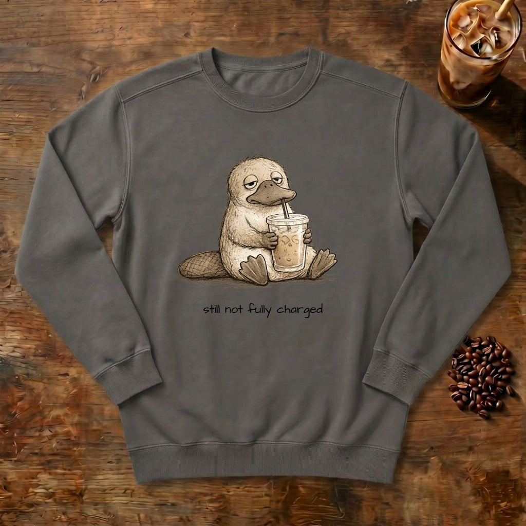 Still Not Fully Charged Platypus Sweatshirt in Pepper, a sleepy platypus sipping iced coffee