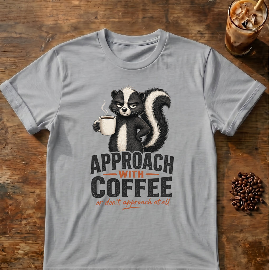 Grumpy skunk holding a steaming coffee mug above bold text reading Approach With Coffee, with orange script below saying or don’t approach at all. Sport Grey
