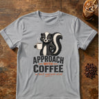 Grumpy skunk holding a steaming coffee mug above bold text reading Approach With Coffee, with orange script below saying or don’t approach at all. Sport Grey