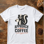 Grumpy skunk holding a steaming coffee mug above bold text reading Approach With Coffee, with orange script below saying or don’t approach at all. White